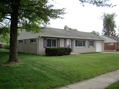 large front tree, grey brick, purple shutters