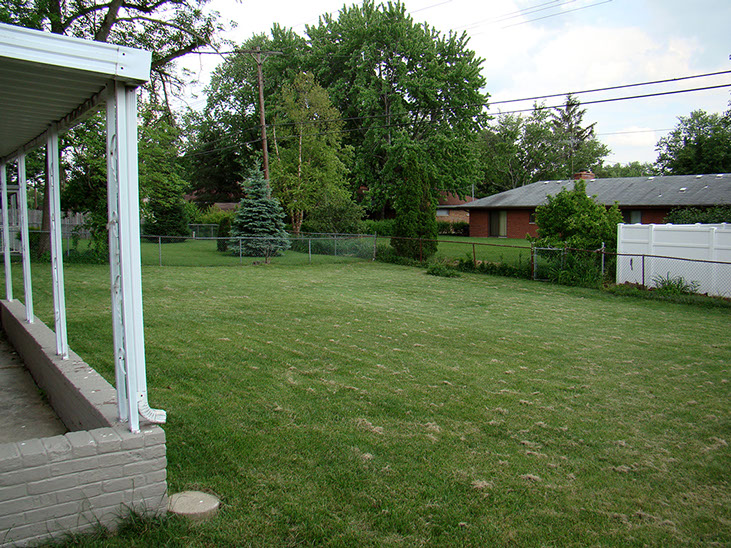 back patio corner, grass, fence, surrounding neighbors